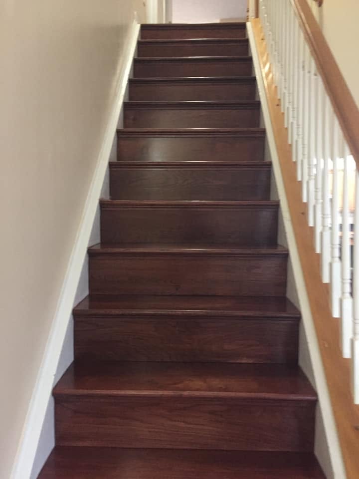Dark stained oak stair treads and risers on a straight staircase after a carpet-to-hardwood conversion